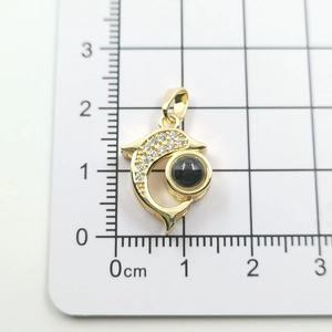 Detailed view of dolphin pendant with white zircon stones and black bead on size scale