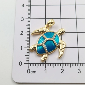 Detailed view of sea turtle pendant with blue enamel and white crystals on a grid scale