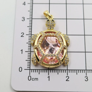 Detail view of turtle pendant with pink crystal and white zircon on a scale ruler