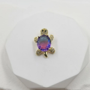Golden sea turtle pendant with a purple-blue gradient gemstone and white zircon stones