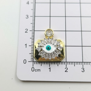 Macro shot of gold-plated evil eye pendant with size measurements on scale grid