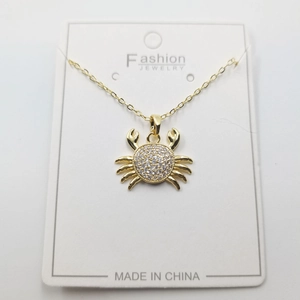 Golden crab pendant necklace featuring sparkling cubic zirconia on a white card display