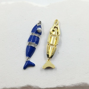 Dettaglio di ciondoli a forma di pesce in smalto blu snodabili con occhi di perle su pietra