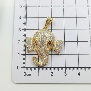 Vue détaillée du pendentif éléphant en or avec zircons blancs et yeux rouges sur grille