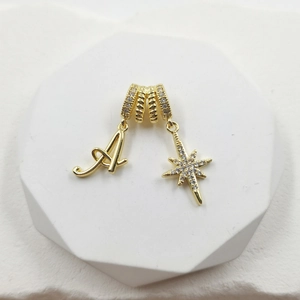 Detailed macro view of gold-plated letter A and star pendants with pavé-set zircons