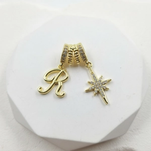 Macro view of gold plated pendant with pavé zircon letter R and North Star details