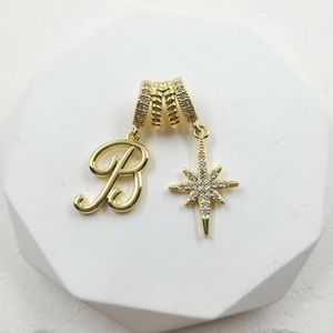 Detailed view of a gold zodiac star pendant with zircon stones and letter B charm