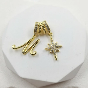 Detailed macro of a gold M-letter and star pendant with sparkling pavé zircons