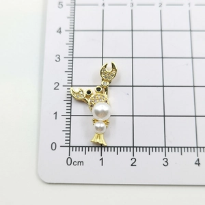 Detailed view of a lobster pendant with gold plating, pearls, and zircons on a metric ruler