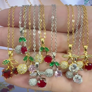 Dettaglio di collane con ciondolo a ciliegia e zirconi colorati in finitura oro e argento