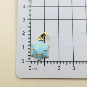 Close-up of light blue enamel turtle pendant on a measurement grid showing 1.5cm width
