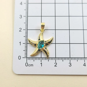 Detailed macro view of a gold starfish pendant with zircon stones on a measuring scale