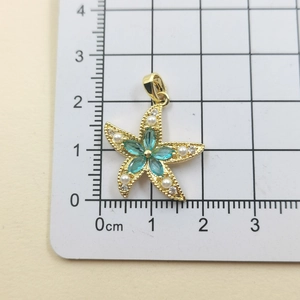 Macro shot of starfish pendant with blue crystals and pearls on a white grid scale