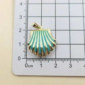 Detail of a gold scalloped shell pendant with turquoise enamel on a measurement grid