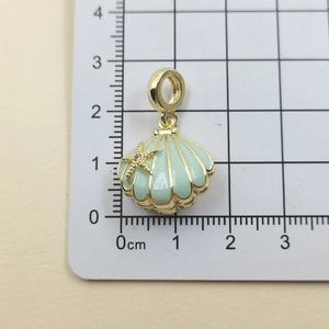 Macro shot of mint green shell pendant with gold starfish on 1.5cm measuring scale