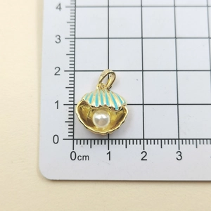 Macro shot of seashell pendant with blue enamel and pearl, measuring 1.5cm by 1.7cm
