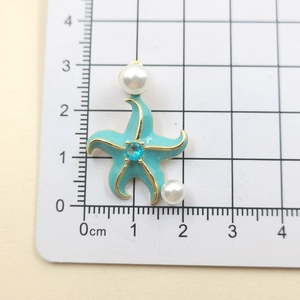 Macro shot of blue starfish pendant featuring gold edges, pearls, and zircon crystal