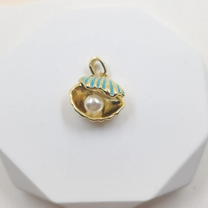 Golden shell pendant with blue enamel and a white pearl on a white pedestal