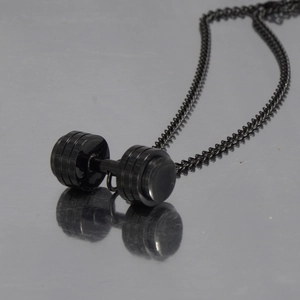Close-up of black stainless steel dumbbell pendant with detailed circular engraving