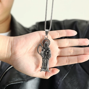 Vue détaillée du pendentif Santa Muerte sur la paume montrant l'artisanat du métal