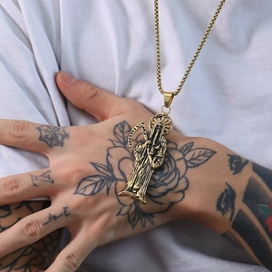 Détail du pendentif faucheuse dorée rétro sur chaîne box porté par un mannequin tatoué