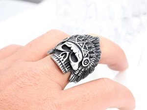 Detalle de anillo de calavera vintage en acero de titanio con plumas indias