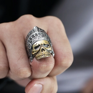 Detalle de un anillo de calavera vintage con plumas doradas usado por un modelo