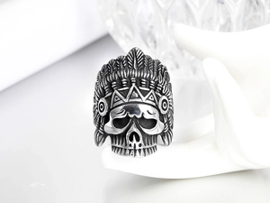 Detalle de anillo de calavera india de acero vintage con tocado de plumas en una mano