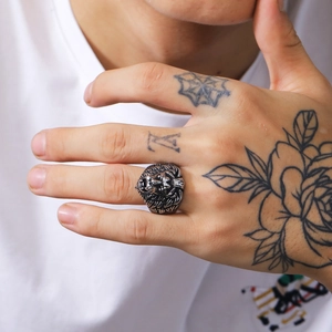 Detailed close-up of a masculine punk lion head ring on a tattooed hand