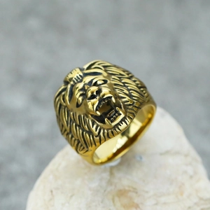 Close-up of a gold-toned men's lion head ring with vintage punk style on a stone base
