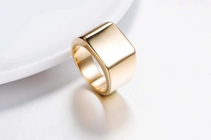 Vue macro d'une bague chevalière carrée dorée polie avec une surface en métal lisse