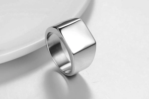 Gros plan d'une bague chevalière carrée polie minimaliste sur une assiette