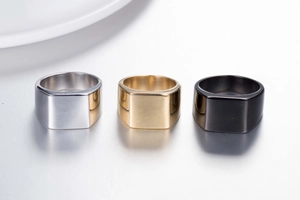 Détail de bagues larges en acier titane en argent, or et noir avec dessus plat