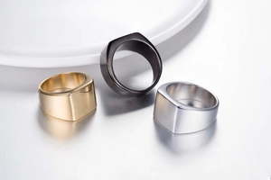Bagues chevalières polies en acier titane or noir et argent sur surface en céramique