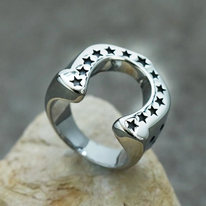 Macro shot of silver horseshoe ring with black star engravings on polished stainless steel