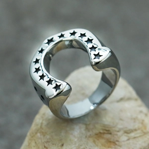 Macro shot of horseshoe-shaped steel ring with engraved stars on a textured stone