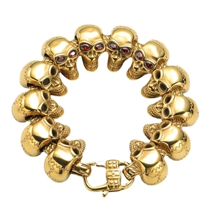 Dettaglio bracciale teschio dorato con occhi di pietre rosse e chiusura a moschettone