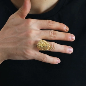 Macro detail of golden lion head ring showcasing embossed metal texture and relief carving