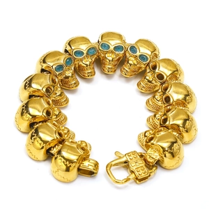 Dettaglio del bracciale con teschi, occhi turchesi e chiusura a moschettone in oro