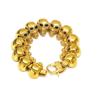 Dettaglio di un bracciale a teschio dorato stile punk con occhi in zircone e chiusura a moschettone