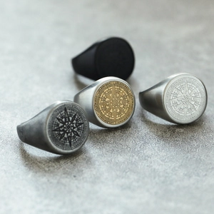 Primer plano de anillos de sello de acero inoxidable con grabado de brújula en varios tonos