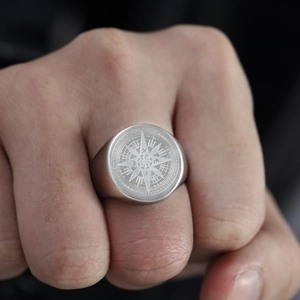 Detalle de un anillo de sello para hombre en acero inoxidable con brújula grabada punk