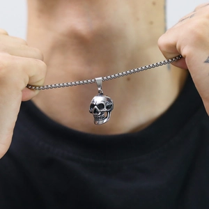 Macro shot of punk style stainless steel skull pendant with vintage box chain on model