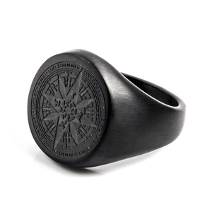 Detalle de un anillo de brújula negro mate con grabado LUCLEON MMXI en el borde exterior