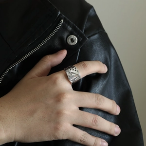 Close-up of vintage steel poker aces ring on hand with a leather jacket background
