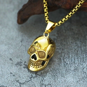Macro detail of gold skull pendant with intricate textures on a classic box chain