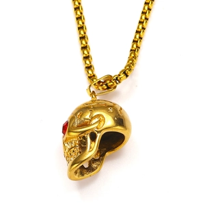 Macro detail van de gouden schedelhanger met rode edelsteenogen op een boxketting
