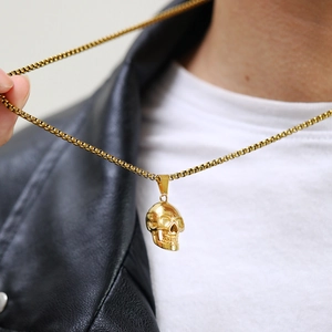 Close-up of golden skull pendant necklace on male model wearing black leather jacket