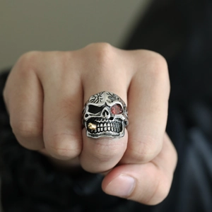 Macro shot of a punk skull ring with red eye gemstone and gold pipe detail for men