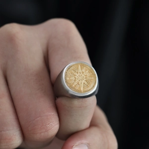 Detalle de anillo de sello para hombre en acero con motivo de brújula en oro y plata